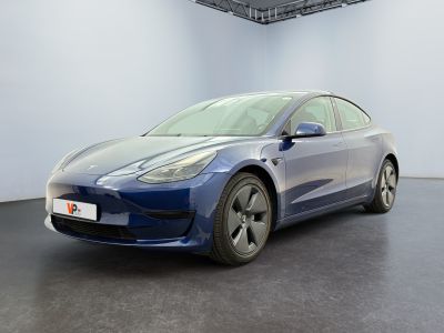 une Tesla Model 3 bleue garée dans une pièce blanche