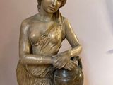 a statue of a woman with a pot on a table