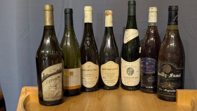 several bottles of wine are lined up on a wooden table