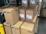 des cartons empilés sur des palettes dans un grand entrepôt, avec des palettes au premier plan