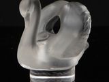 a clear glass sculpture of a swan on a black surface