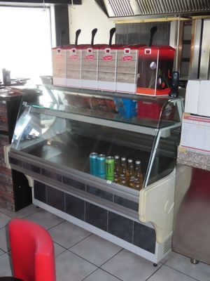 un comptoir réfrigéré dans un restaurant, avec des sodas posés dessus