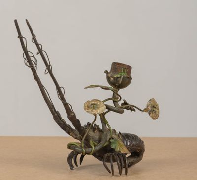 sculpture en bronze représentant une femme assise sur un crabe, tenant une fleur à la main