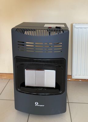 un radiateur noir posé sur un sol carrelé, à côté d'un radiateur