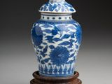 blue and white vase with lid on stand on grey background