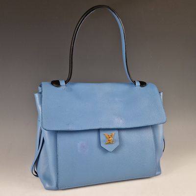 un sac à main en cuir bleu orné d'un emblème doré sur le devant