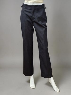 un mannequin féminin portant un haut blanc et un pantalon noir à fines rayures