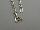boucles d'oreilles en chaîne plaquée argent avec la lettre « a » sur fond gris