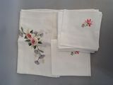 trois serviettes blanches ornées de fleurs roses, posées sur une table