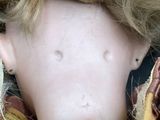 a close up of a doll ' s face with a stuffed animal