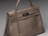 a beige leather handbag with a metal handle on a gray background