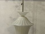 a white lamp hanging from a chain on a wall