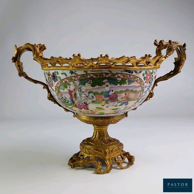 un grand vase décoré, posé sur un socle doré, avec un fond blanc
