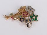 un gros plan d'une broche ornée de fleurs et de feuilles