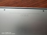 the back of a silver laptop sitting on top of a wooden table