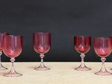six red wine glasses lined up on a wooden table