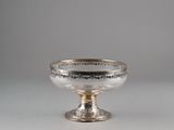 an antique silver footed bowl on a pedestal on a gray background