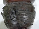 un vase marron orné d'un dragon, posé sur une table