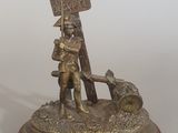 figurine en bronze représentant un homme tenant une pancarte et accompagné d'un chien