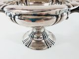 a silver bowl with a handle on a white surface
