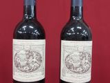 two bottles of wine sitting on top of a red table