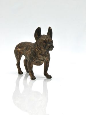 a small bronze statue of a dog on a white surface