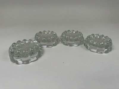 four clear glass dishes on a white table with a white background