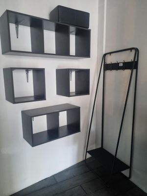 une étagère noire avec un porte-manteau et un porte-manteau fixé au mur