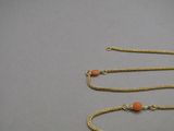 an image of a gold chain with a red bead on it