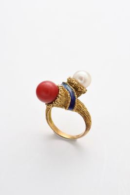 un gros plan sur une bague en or sertie d'une pierre rouge et d'une perle