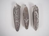 three silver spoons sitting on top of a white table next to each other