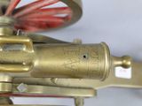 a close up of a brass clock with a red wheel on it