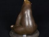 statue of a brown bear sitting on a base with a black background