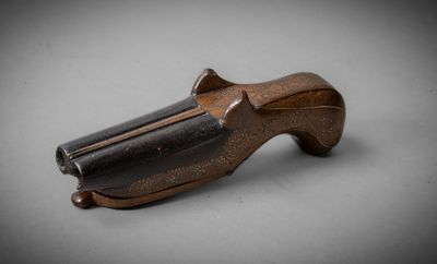 un gros plan d'un pistolet posé sur une table, sur fond gris
