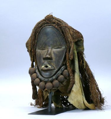 un masque posé sur un support, sur une surface blanche