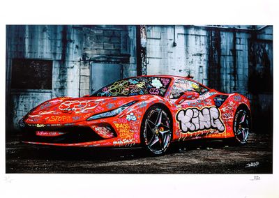 red sports car with graffiti on it parked in front of a building