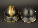 two helmets with gold trims are sitting on a black surface