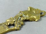a gold spoon with grapes and a tennis racket on it