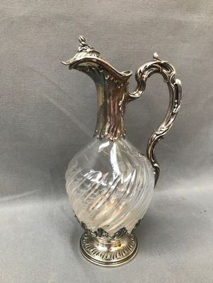 an antique silver plated glass pitcher with a curved handle