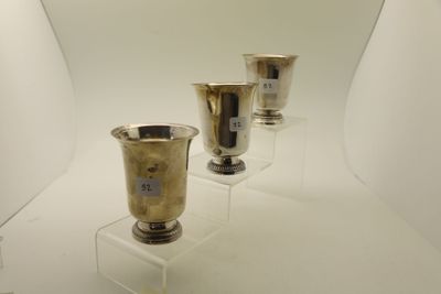 trois vases en argent exposés dans une pièce blanche