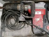 a red and black drill and some other tools on a table