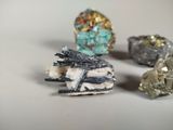 three pieces of rock with different colored crystals on a white surface