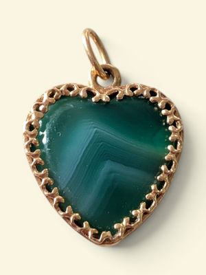 a green heart shaped pendant with a gold plated frame
