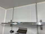 une étagère en acier inoxydable au-dessus d'une cuisinière dans une cuisine