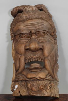 une vieille sculpture en bois représentant le visage d'un homme, posée sur une table