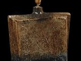 un vase marron et noir posé sur une table noire