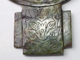 a metal object with a design on it on a white surface