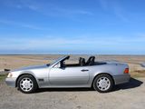 mercedes sl - class convertible parked on the side of the road near the ocean