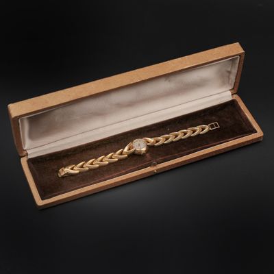 a close up of a watch in a wooden box on a black background