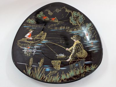 a black plate with a picture of a man fishing